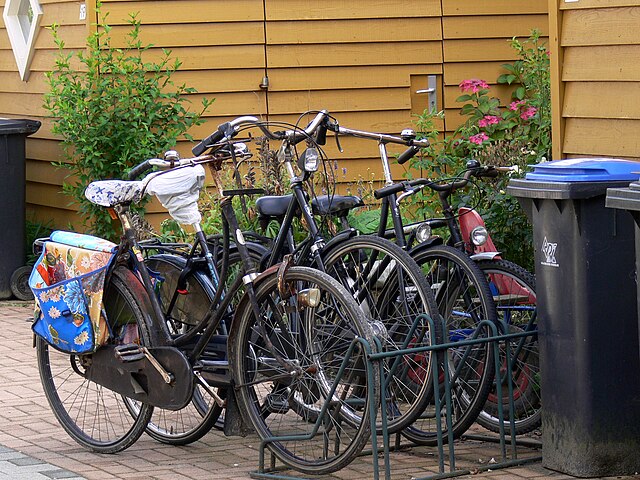 A group of bicycles parked on a sidewalk Description automatically generated