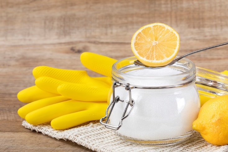 A lemon on a spoon in a jar with a lemon wedge on top Description automatically generated