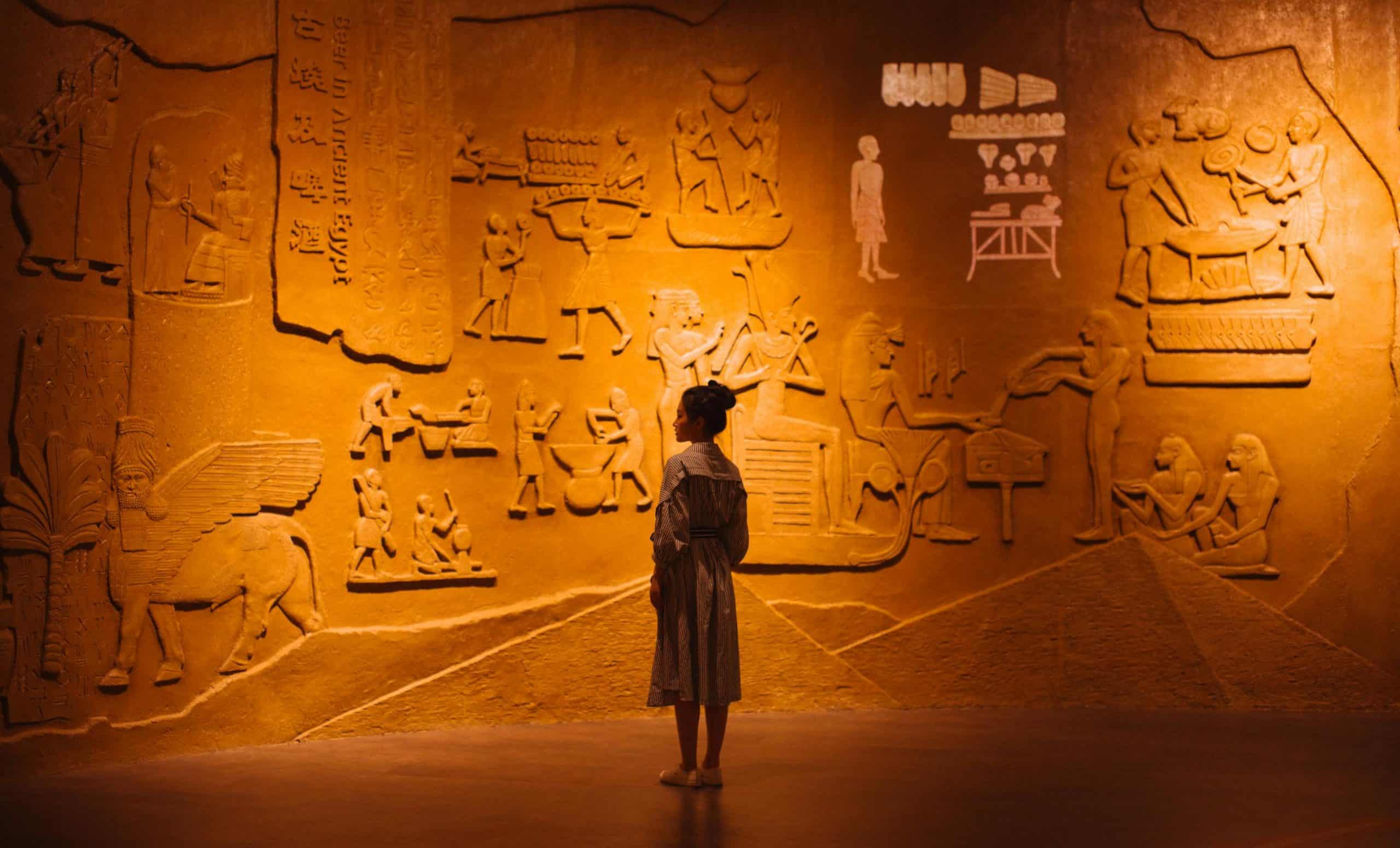A woman standing in front of a stone with carved images