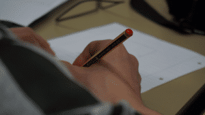 Hand holding a pencil writing on lined paper